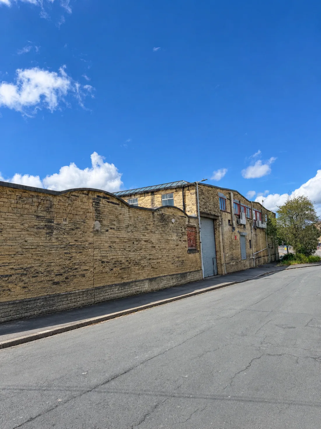 The long Yorkshire-stone perimeter wall of St Stephens Mill stretching down Ripley Street, Bradford — showing the substantial scale of the self-storage building